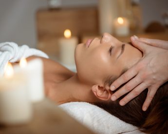 Young beautiful brunette girl having face massage relaxing in spa salon. Eyes closed. Copy space.